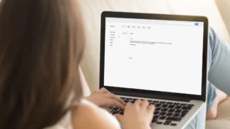 Candidate qui écrit un e-mail de remerciement sur son ordinateur confortablement installée dans son canapé