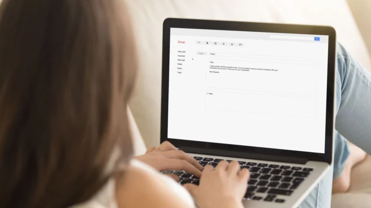 Candidate qui écrit un e-mail de remerciement sur son ordinateur confortablement installée dans son canapé