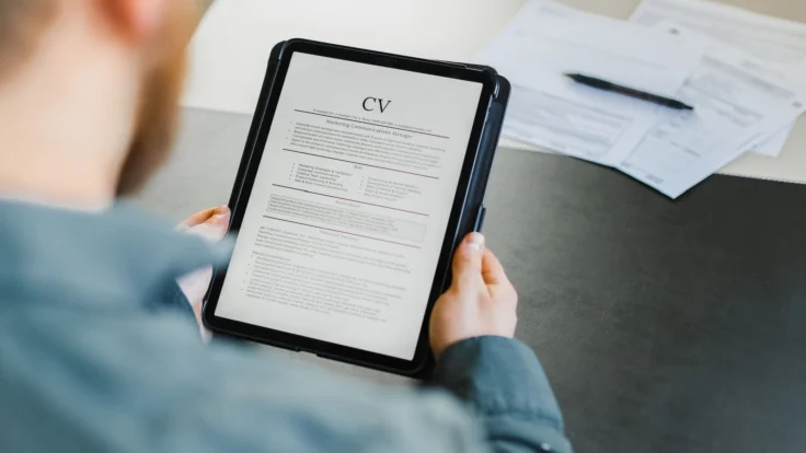 Candidat qui relit son CV et sa mise en page sur sa tablette avant de l'envoyer au recruteur