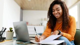Candidate qui fait la liste de ses points forts dans un carnet avant d'écrire sa lettre de motivation