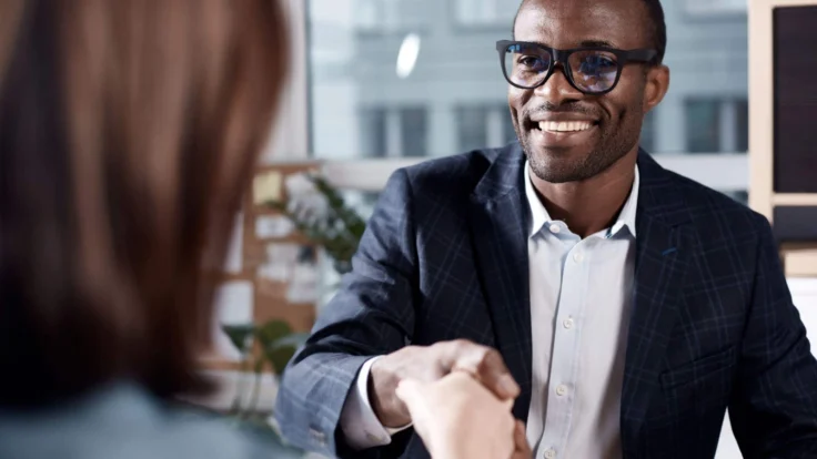 Candidat qui serre la main d'une recruteuse à la fin d'un entretien d'embauche
