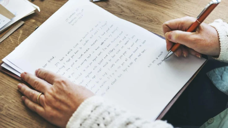 Personne qui signe une lettre manuscrite avec un stylo