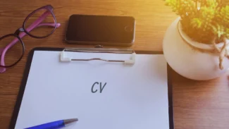 Feuille en papier où est inscrit le mot CV posée sur un bureau