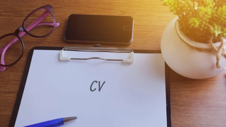 Feuille en papier où est inscrit le mot CV posée sur un bureau