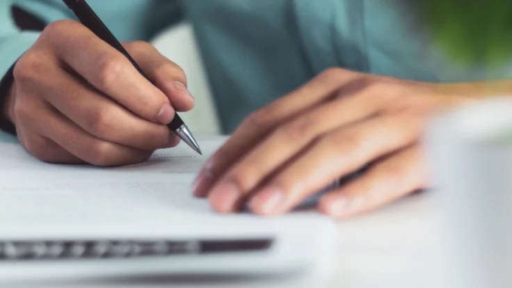 Candidat qui écrite une lettre de motivation à la main avec un stylo