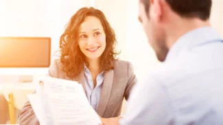 Recruteur qui examine le CV de la candidate assise en face de lui pendant un entretien d'embauche