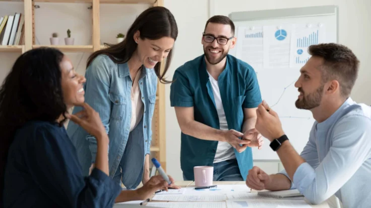 Quatre collègues qui discutent et rient pendant une réunion professionnelle