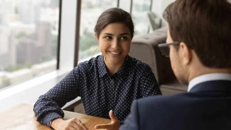 Candidate souriante qui parle de son parcours à un recruteur lors d'un entretien d'embauche
