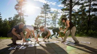 Cinq collègues participant à un team building à l'extérieur lors d'une journée de beau temps