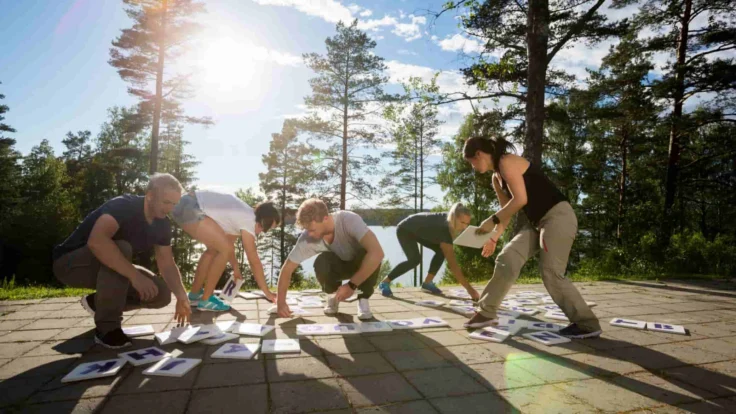 Cinq collègues participant à un team building à l'extérieur lors d'une journée de beau temps