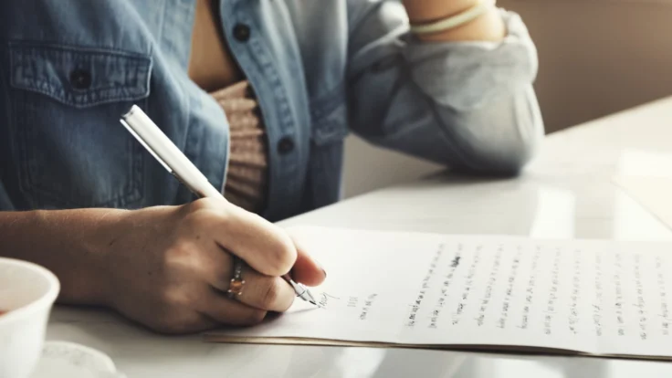 Candidate qui écrit une lettre de motivation à la main et fait quelques ratures