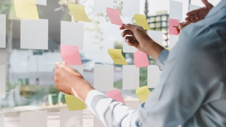 Deux employés font un brainstorming et consultent les idées indiquées sur des posts-its